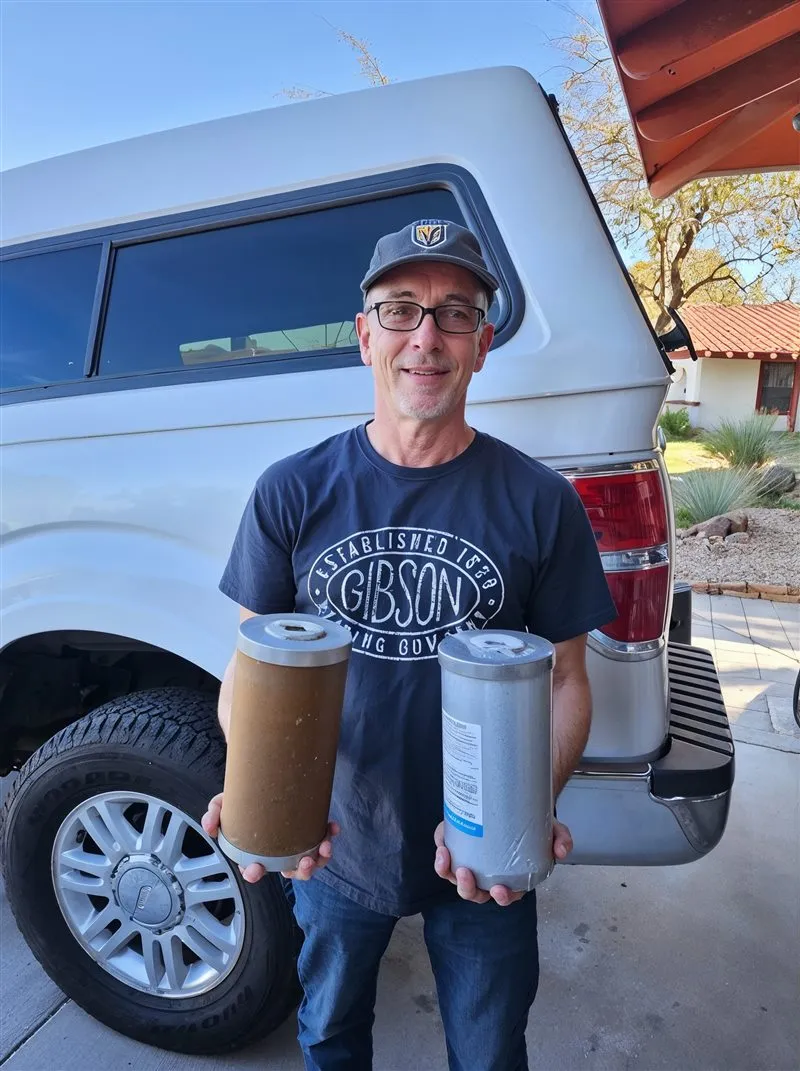 Our installer holding a used sediment filter cartridge next to a brand-new one